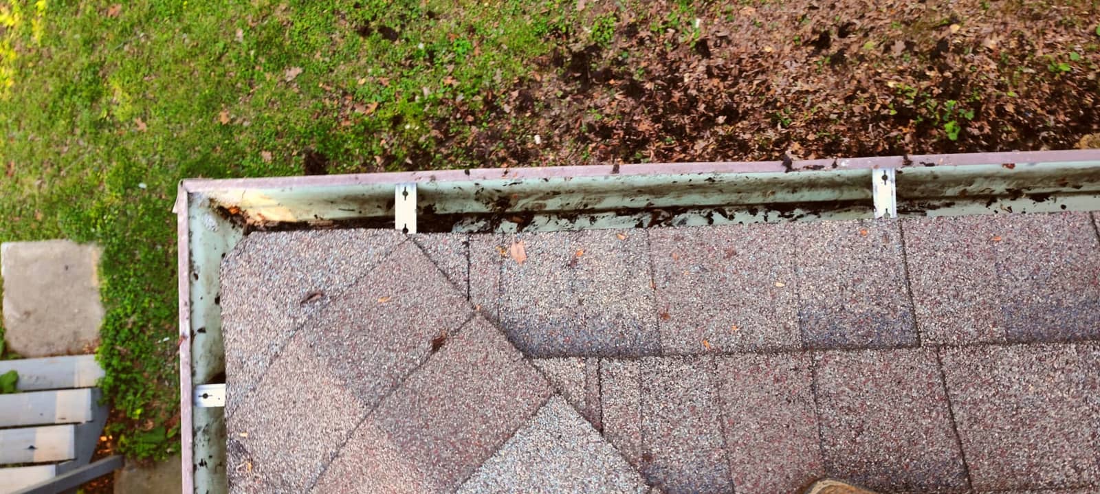 Handful of wet leaves and shingle grit pulled from a clogged residential gutter during Elite Exteriors service
