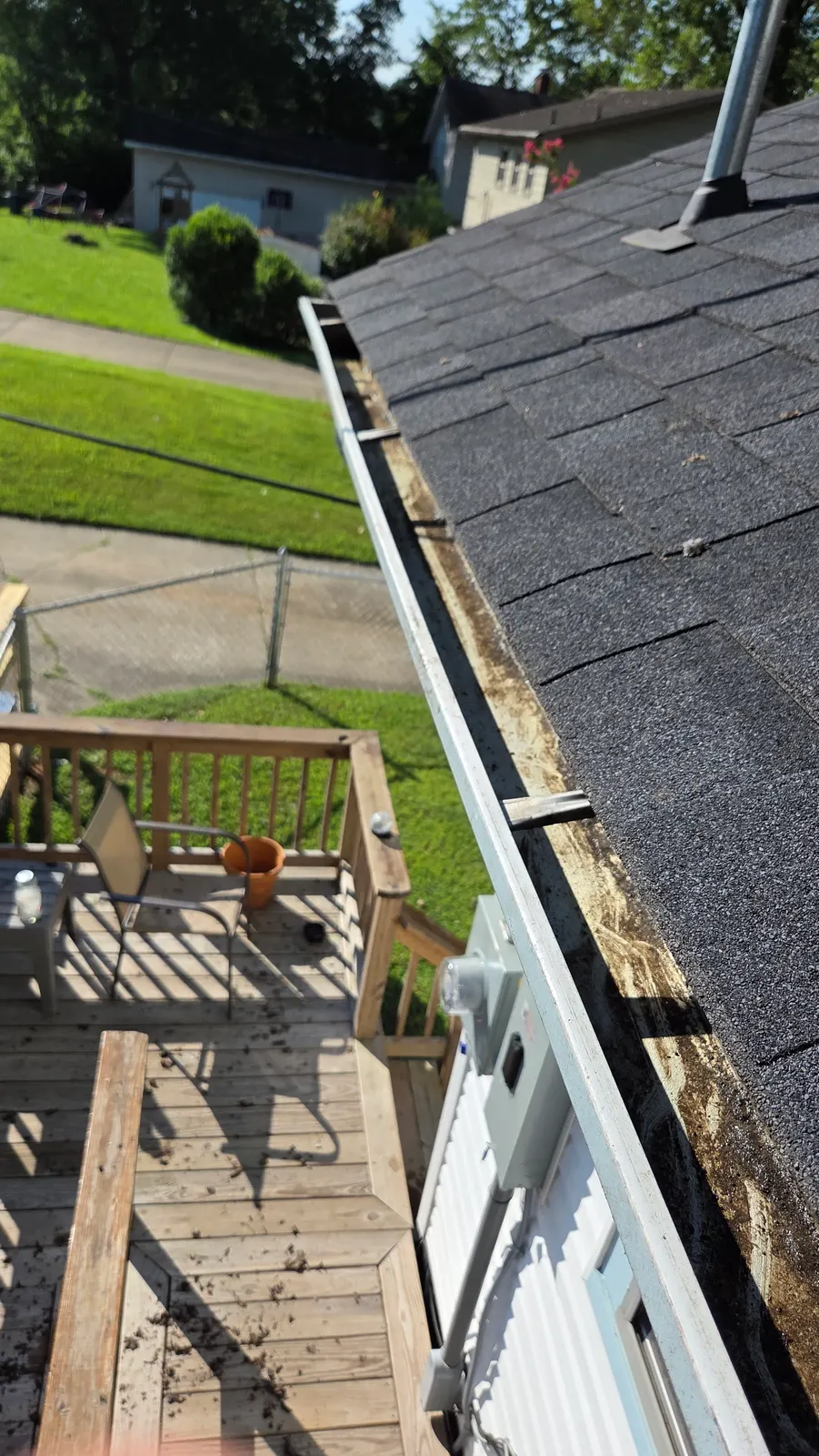 The same roofline gutter cleared of leaves and debris, seen from the roof above the wooden deck.