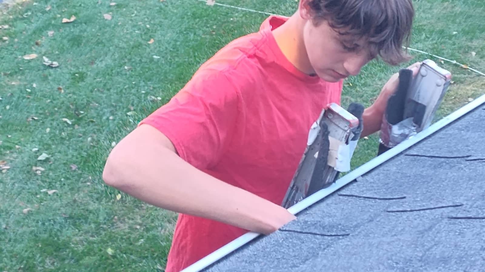 Elite Exteriors technician on a ladder cleaning gutters on a two-story home in Floyds Knobs, IN