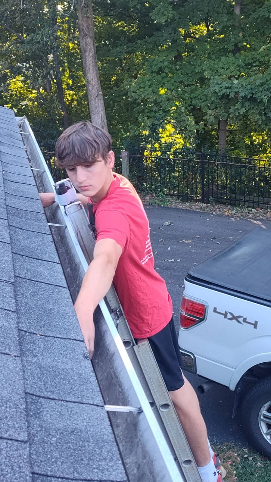 Elite Exteriors team removing leaves and debris from a residential gutter system in Southern Indiana