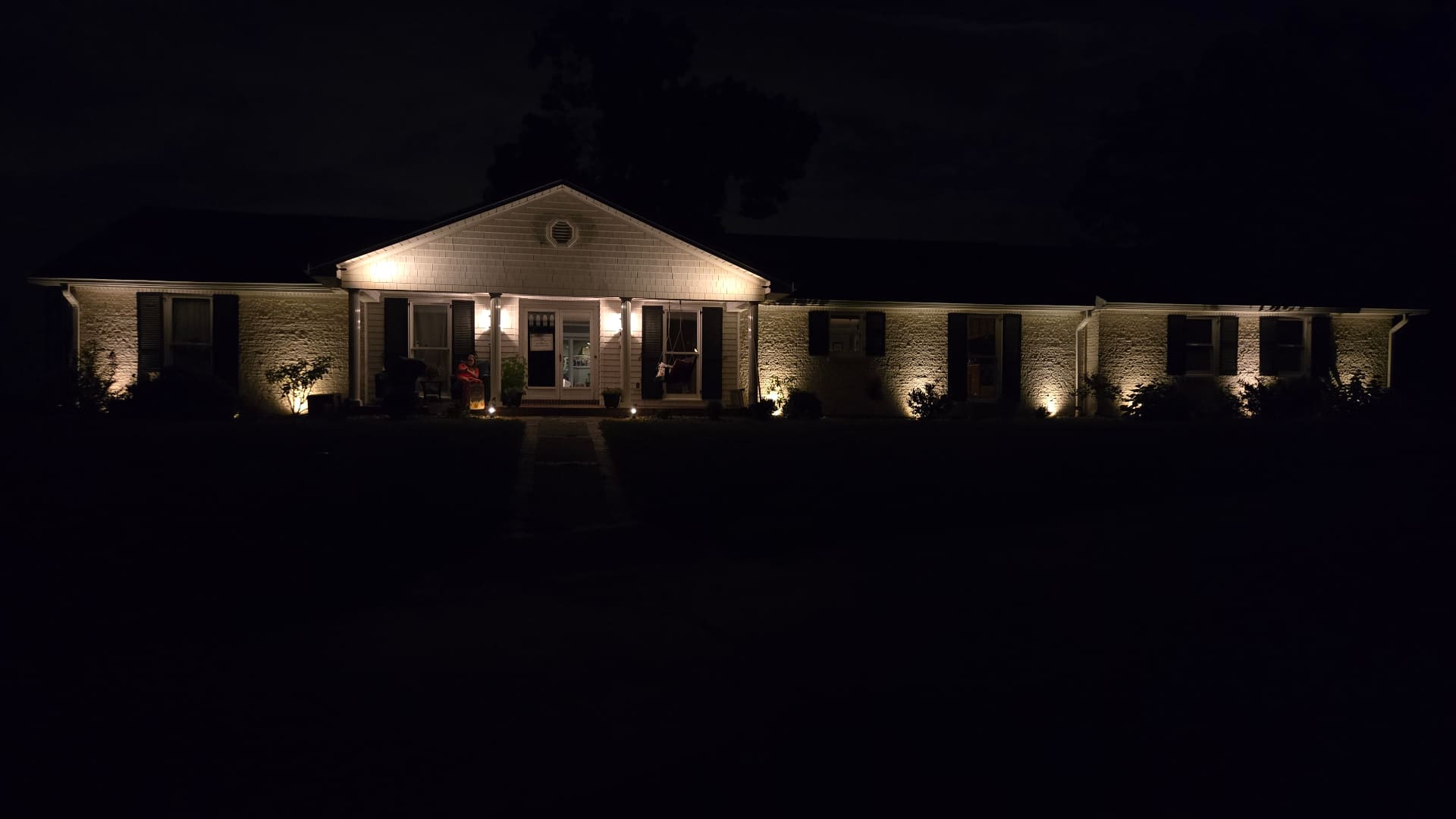 Ranch-style home at dusk with warm-white landscape uplighting installed by Elite Exteriors in Southern Indiana