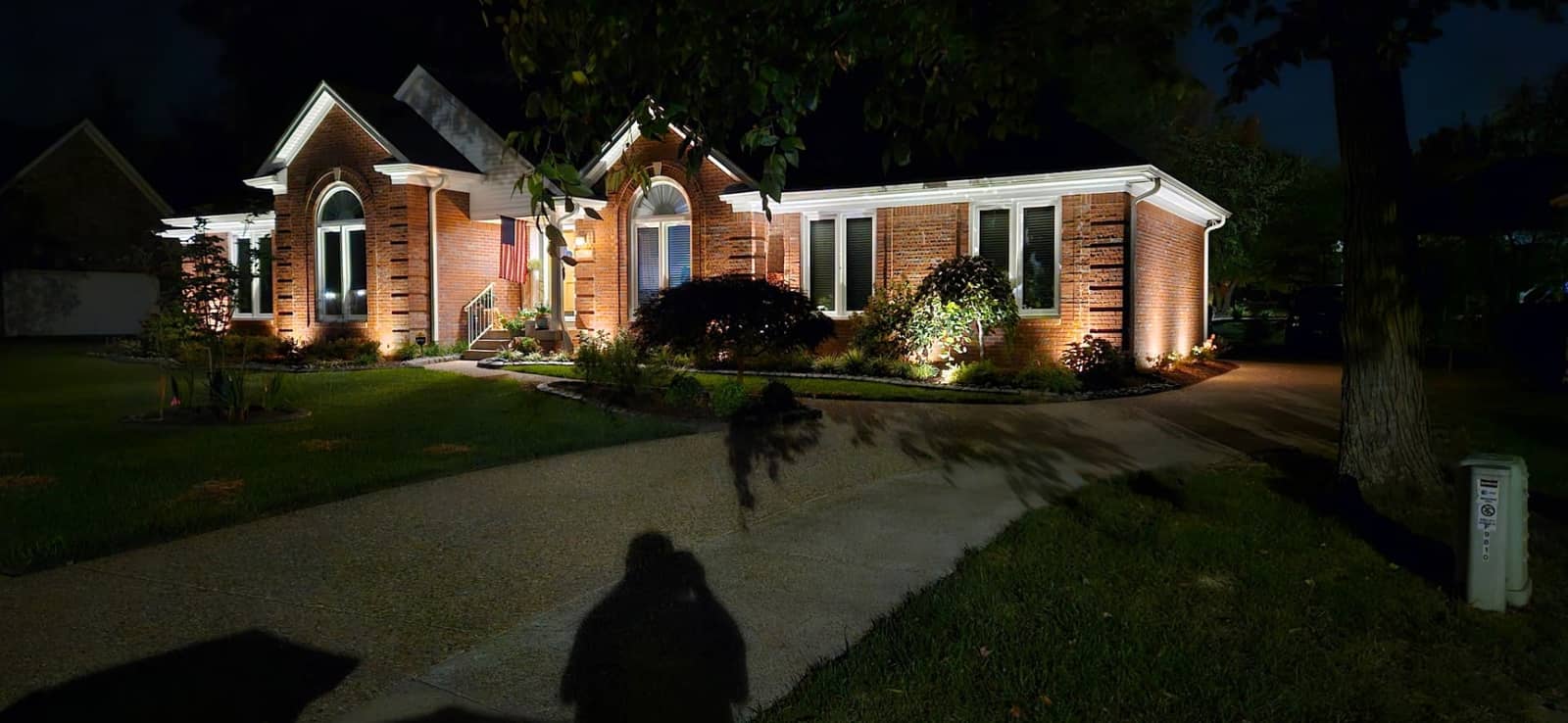 Brick home façade illuminated with landscape accent lighting installed by Elite Exteriors
