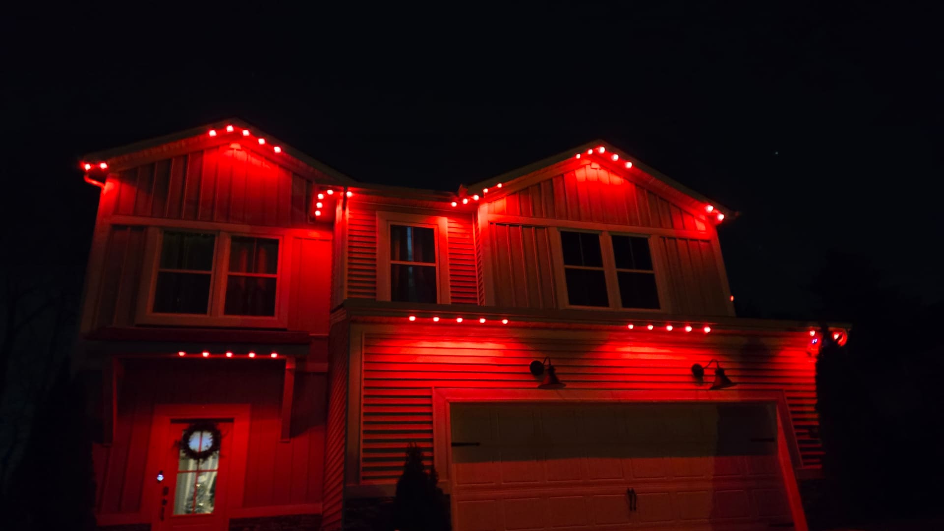 Home roofline showing red accent color mode on Elite Exteriors permanent LED lighting system