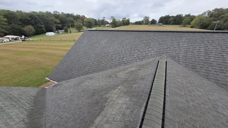 The same shingle roof from the same spot partway through washing, with a lighter cleaned section in the foreground.