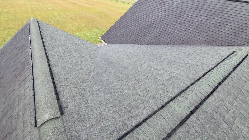 Asphalt shingle roof with dark streaks and discoloration across the slopes, seen from the ridge.