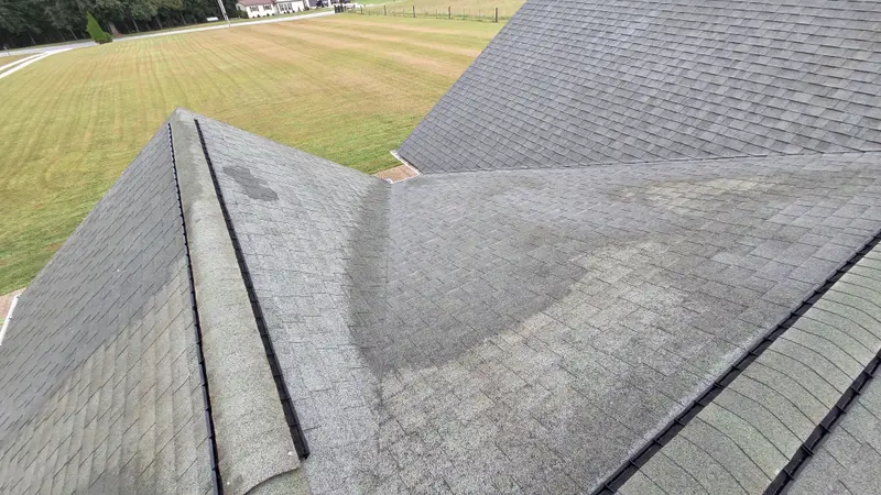 The same shingle roof partway through washing, with lighter cleaned shingles next to the darker untreated area.