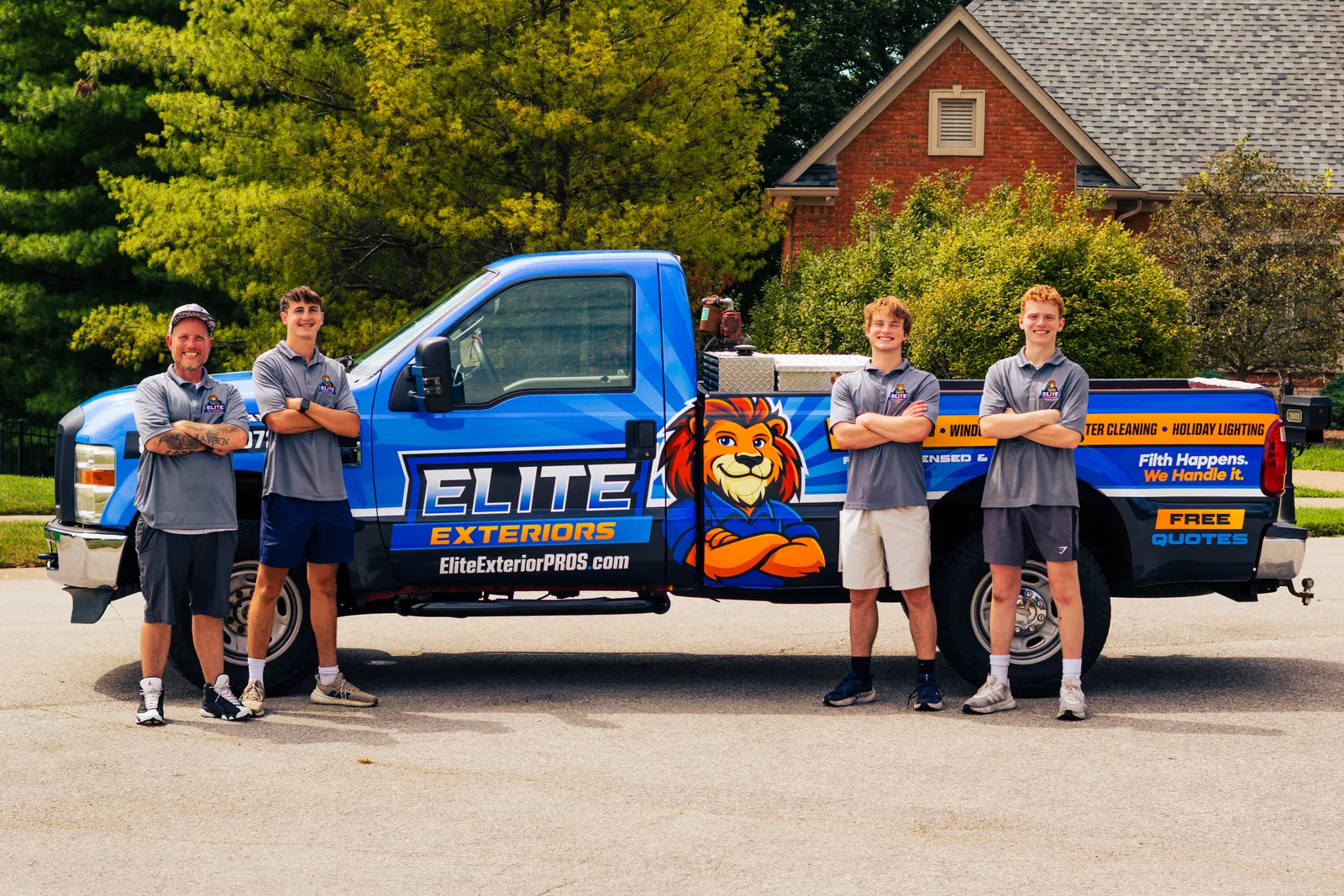 Join the Elite Exteriors team Elite Exteriors crew in gray company polos standing at each end of the blue wrapped Elite Exteriors truck