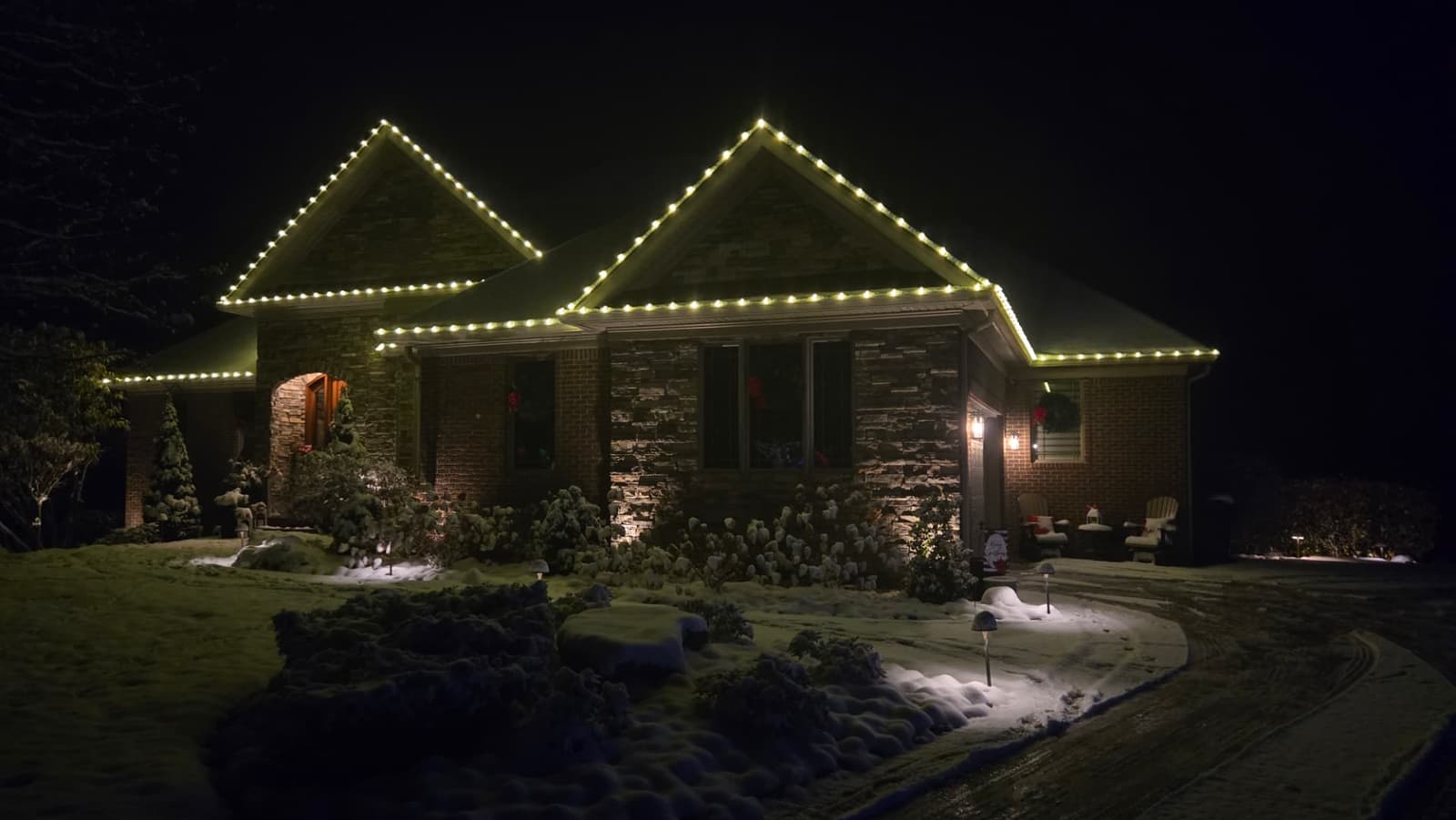 Stone and brick home in Floyds Knobs with warm white C9 Christmas lights on every roof peak